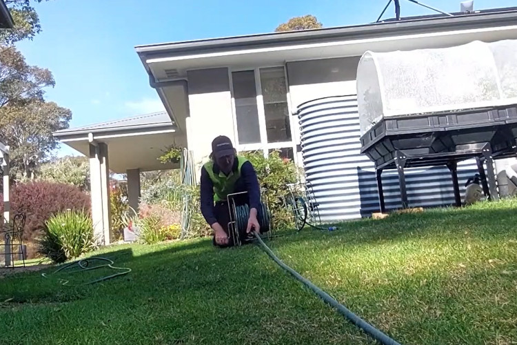 Wrapping up his daily work, the batemansbay downpipe cleaner is neatly storing his hose.